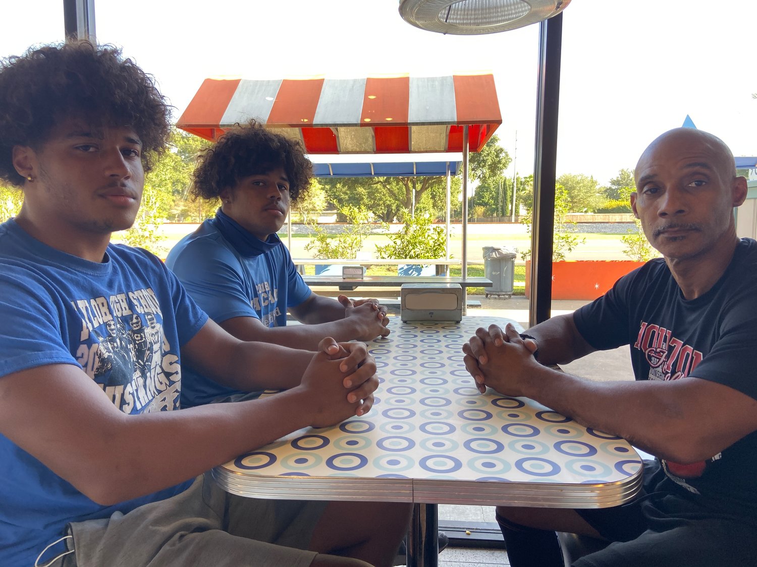On the left, twins Jordan, front, and Marcus Daniels sit with dad Mike at Willy Burger on Sept. 26.